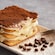 Tiramisu on a plate with a fork and coffee beans